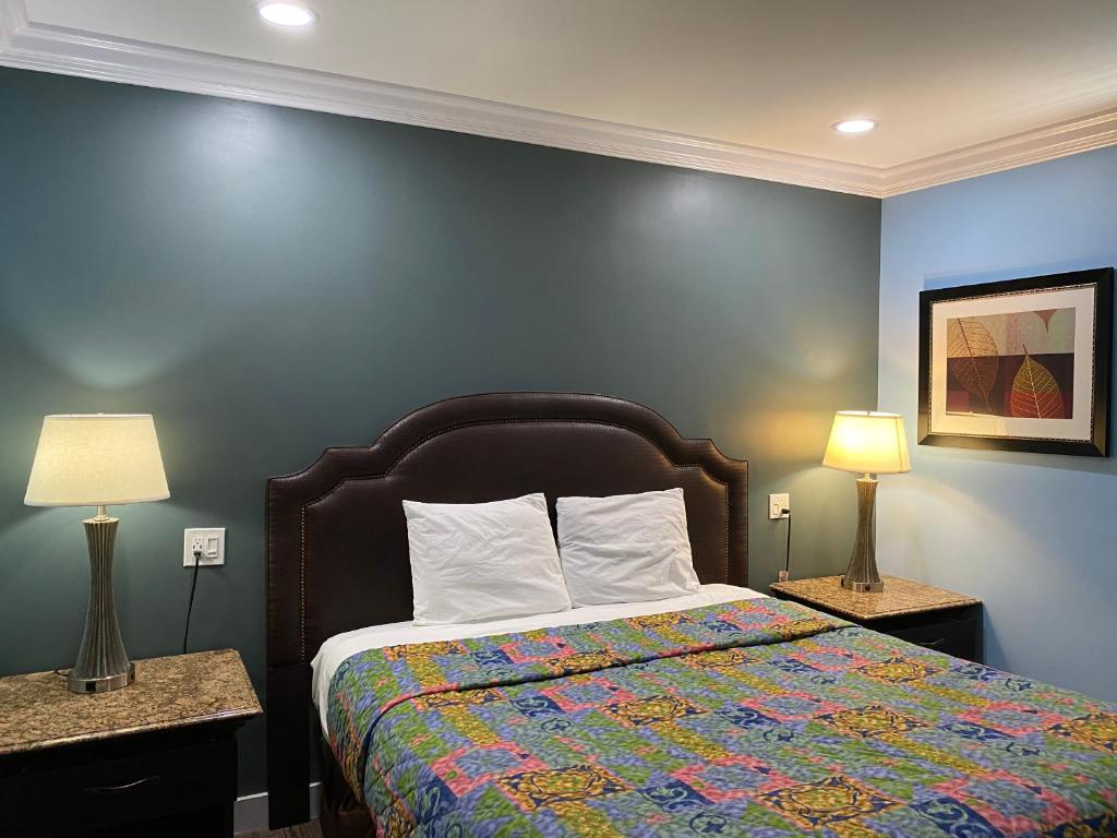Redondo Beach Motel - LAX في غاردينا: غرفة نوم مع سرير وبطانية ملونة ومصباحين