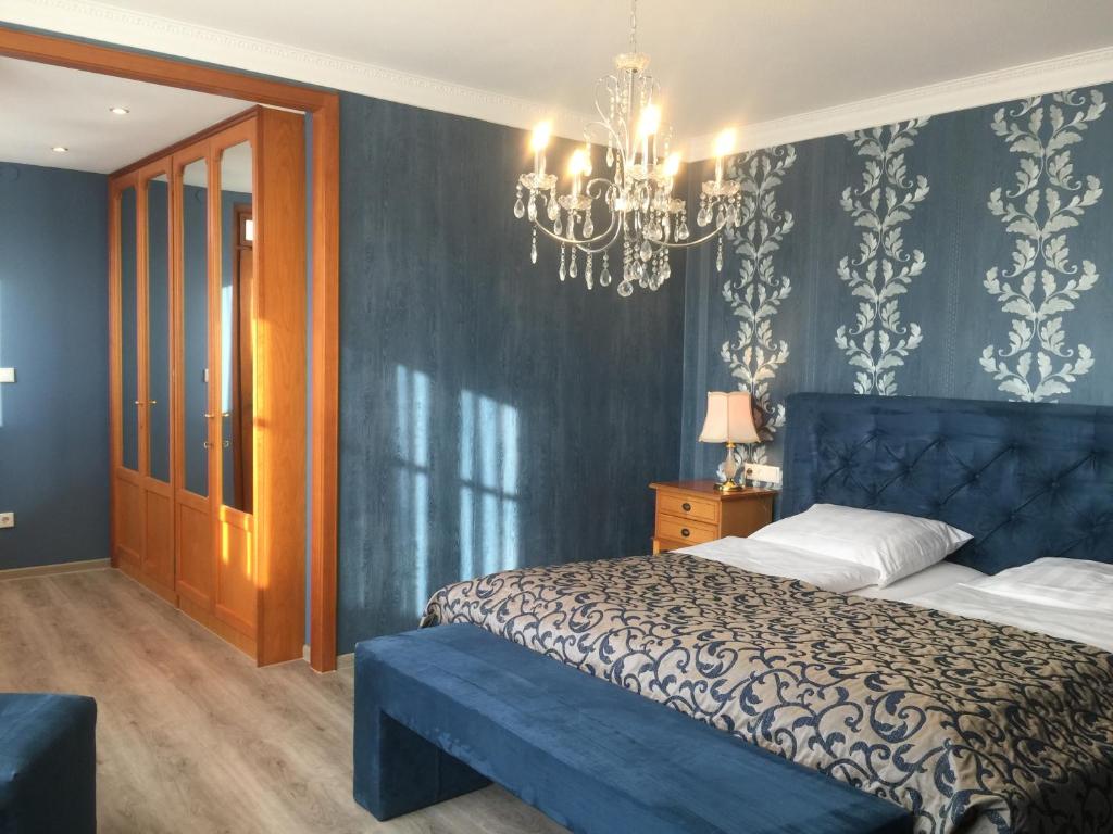 a blue bedroom with a bed and a chandelier at Burghotel in Rothenburg ob der Tauber