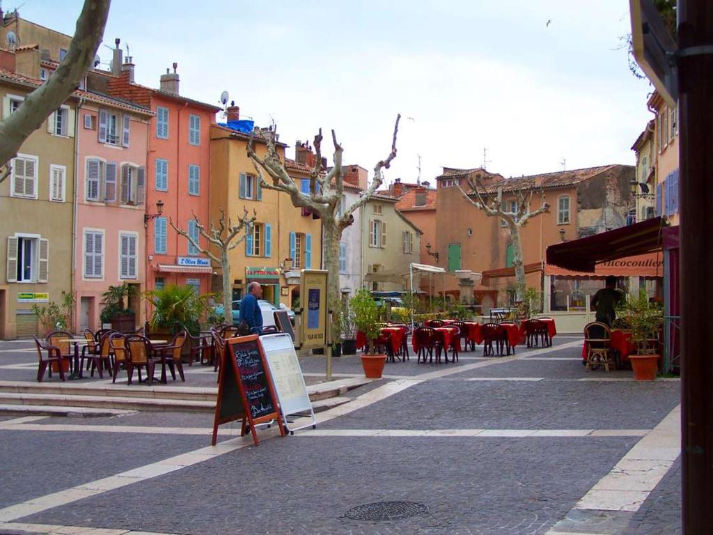 uma rua da cidade com mesas, cadeiras e edifícios em Appartement avec jardin privatif em Fréjus