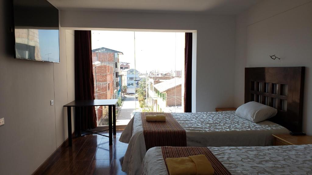 a hotel room with two beds and a large window at La Cabaña Hotel in Cusco