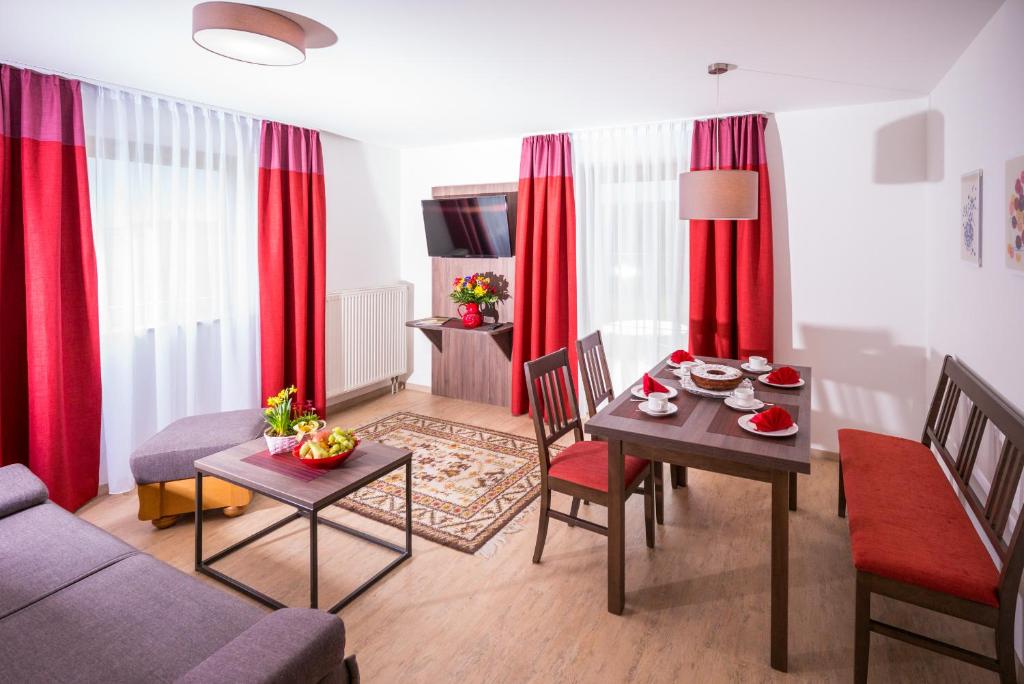 uma sala de estar com uma mesa e cortinas vermelhas em Ferienwohnungen Chiemgauer Seenglück em Obing
