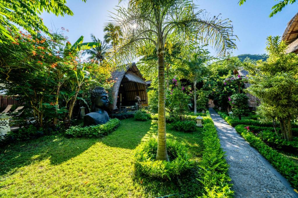 a garden in front of a house with a palm tree at Kelapa Cottage in Amed