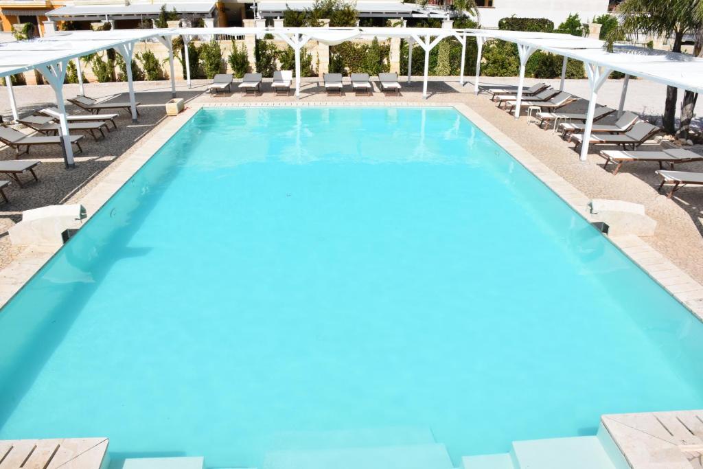 a large swimming pool with lounge chairs and umbrellas at Toto Residence in Torre Lapillo