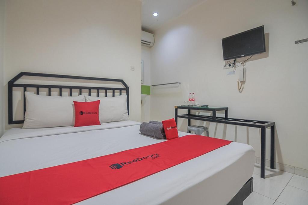 a bedroom with a bed with a red blanket on it at RedDoorz near Nagoya Citywalk Batam 2 in Nagoya
