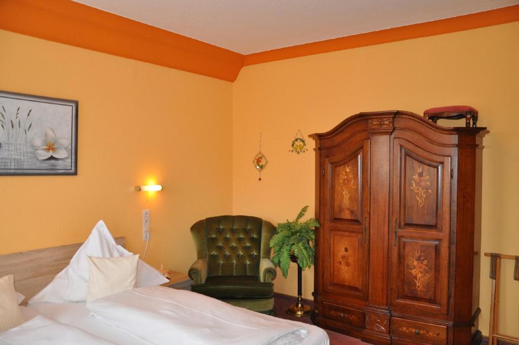 una camera con letto, mobile in legno e sedia di Pension Haus Gertrud a Donauwörth