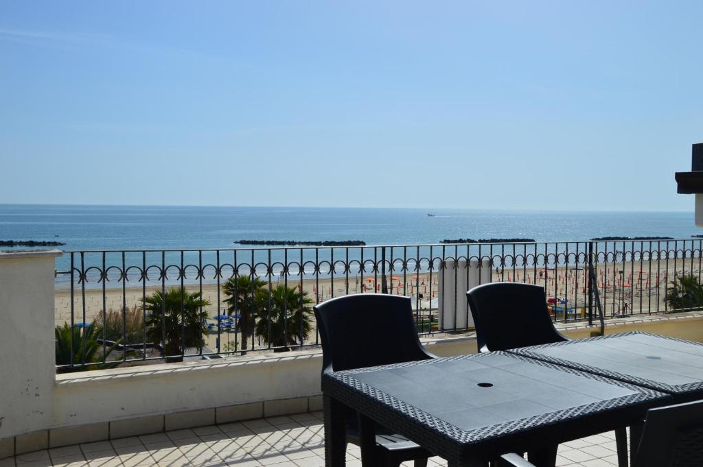 a table and chairs on a balcony with a view of the beach at Mansarda Fronte Mare con servizio spiaggia incluso a Roseto degli Abruzzi in Roseto degli Abruzzi