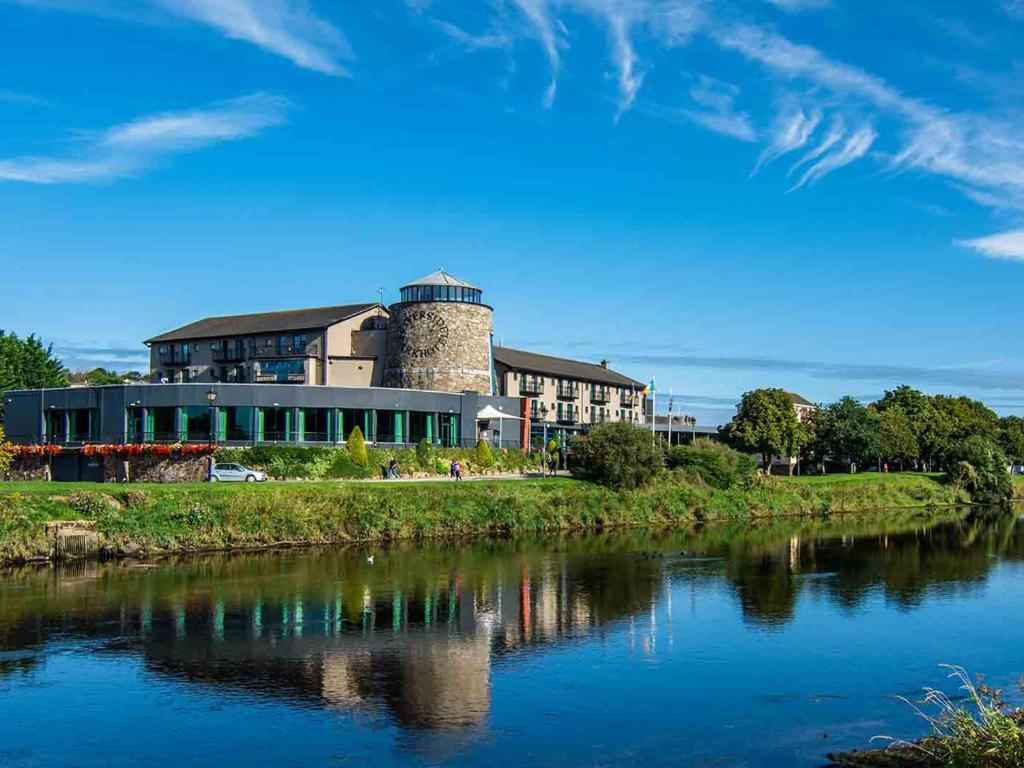 een gebouw met een toren naast een rivier bij The Riverside Park Hotel in Enniscorthy