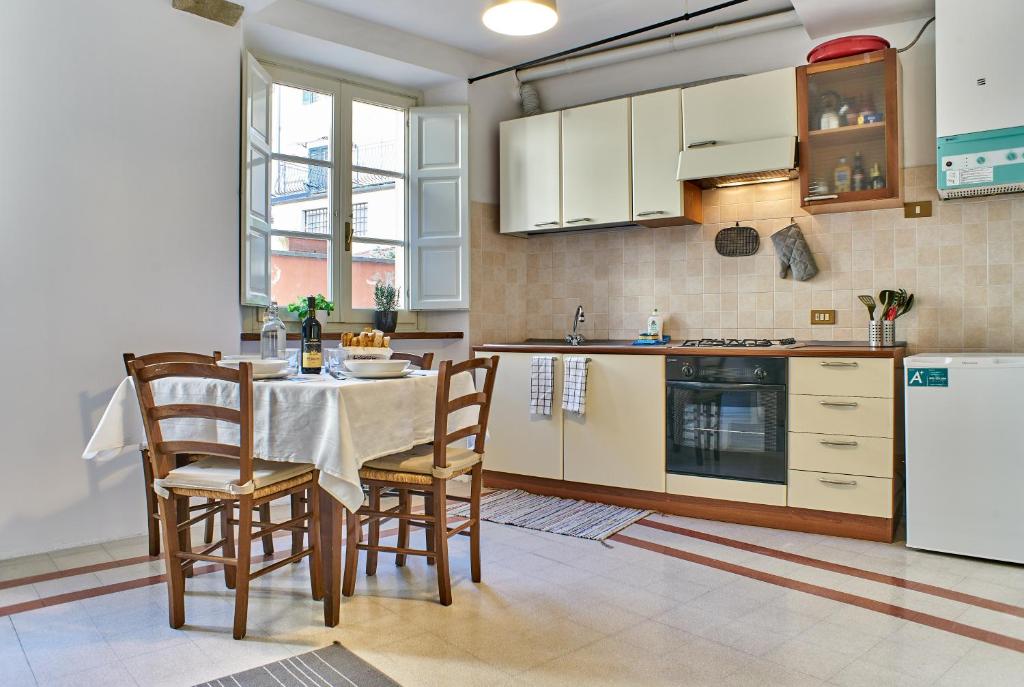 uma cozinha com uma mesa e cadeiras e um frigorífico em Tranquillo bilocale in centro em Lucca
