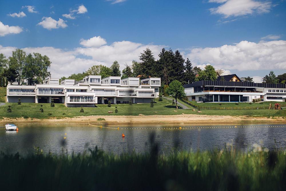 - un grand bâtiment blanc avec un lac en face dans l'établissement SŁONECZNY 1 Lemon Resort Spa, à Gródek nad Dunajcem