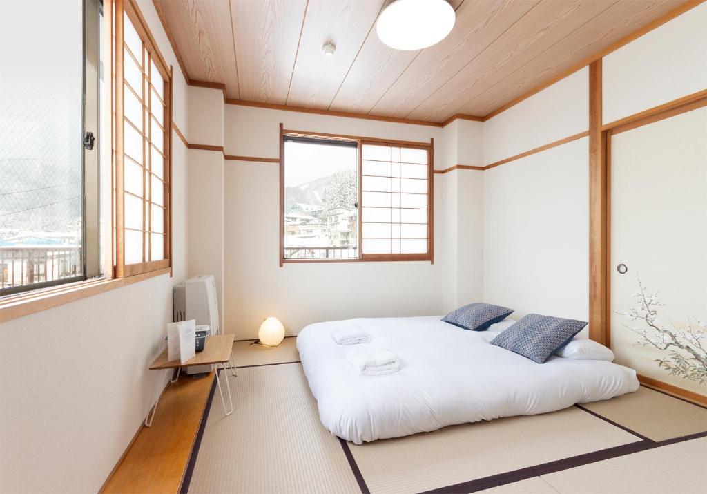 a bedroom with a large white bed and windows at Nozawa Peaks in Nozawa Onsen