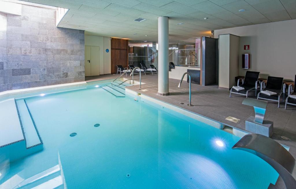 a large swimming pool in a room with chairs at Hostal Trainera in Esterri d'Àneu