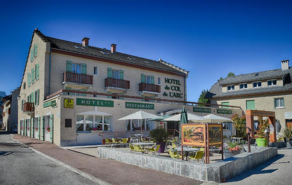 a building with tables and umbrellas on a street at Hotel du Col de l'Arc in Lans-en-Vercors