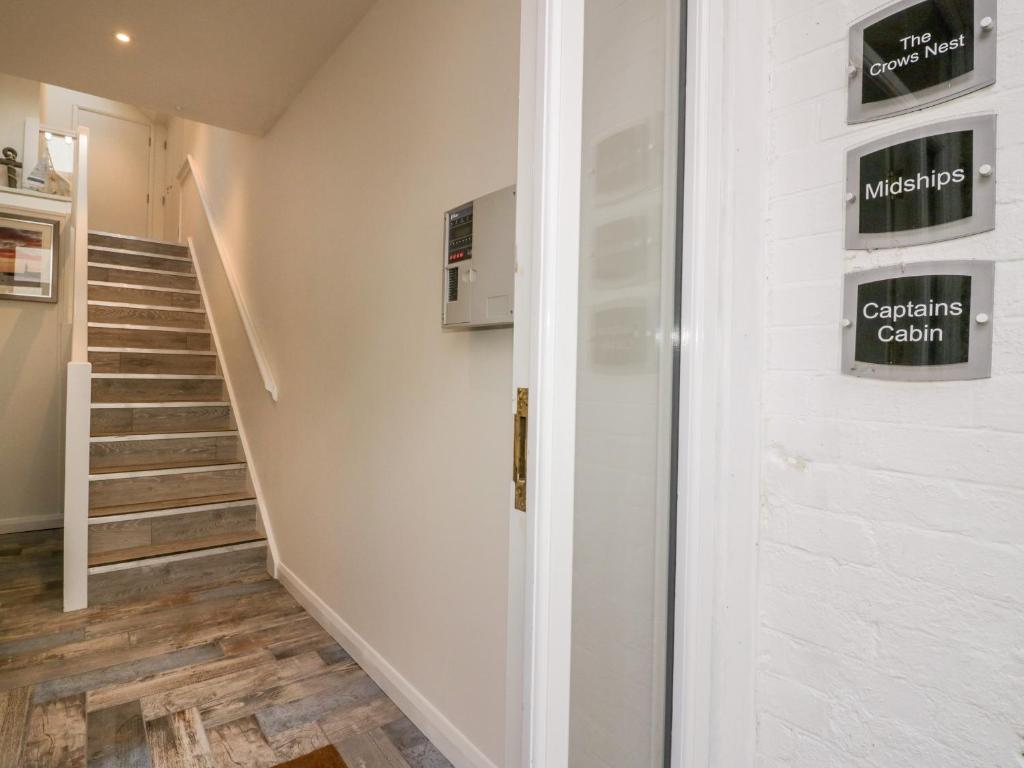 een hal met een trap en een witte deur met borden erop bij Midships in St Austell