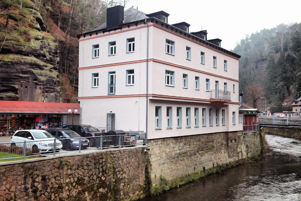 a white building on a wall next to a river at Hotel Kotva in Hřensko