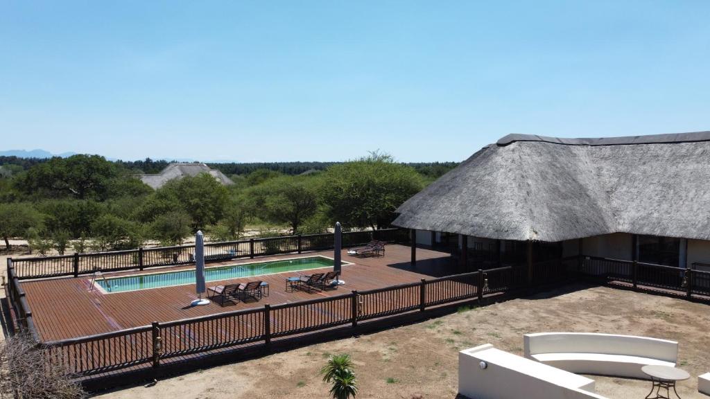 a resort with a swimming pool and a straw roof at Wildlife Estate House With Mountain Views & 12-Meter Pool in Hoedspruit