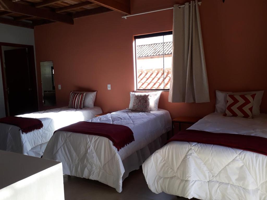 three beds in a room with a window at Dama 2 in Tiradentes