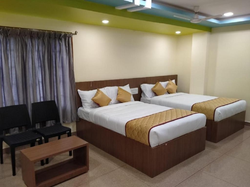 a bedroom with two beds and a chair and a table at SAU Residency in Kanchipuram
