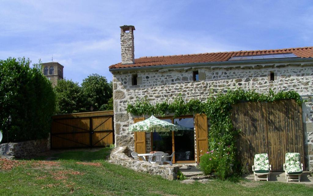 ein Steinhaus mit einem Tisch und Stühlen davor in der Unterkunft Cellier de la Fontaine in Saint-Georges-en-Couzan