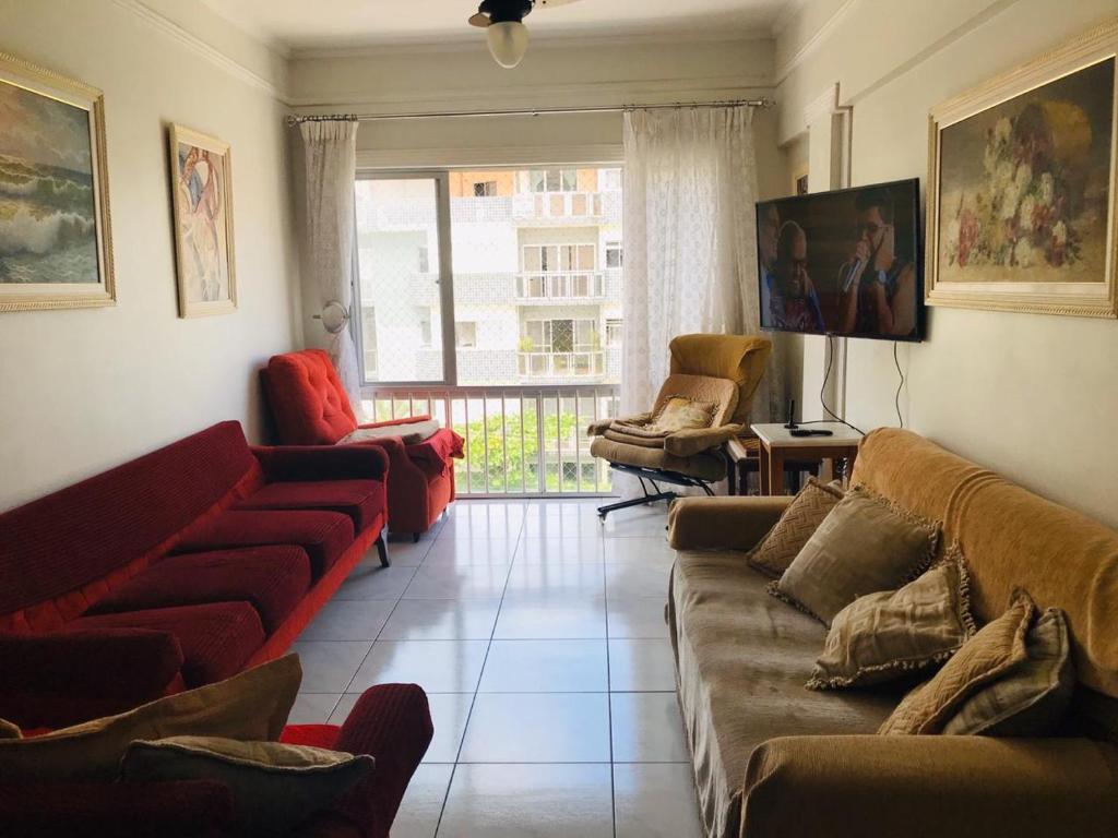 een woonkamer met banken en stoelen en een raam bij Apartamento Astúrias 2 Dorms Ar Cond in Guarujá