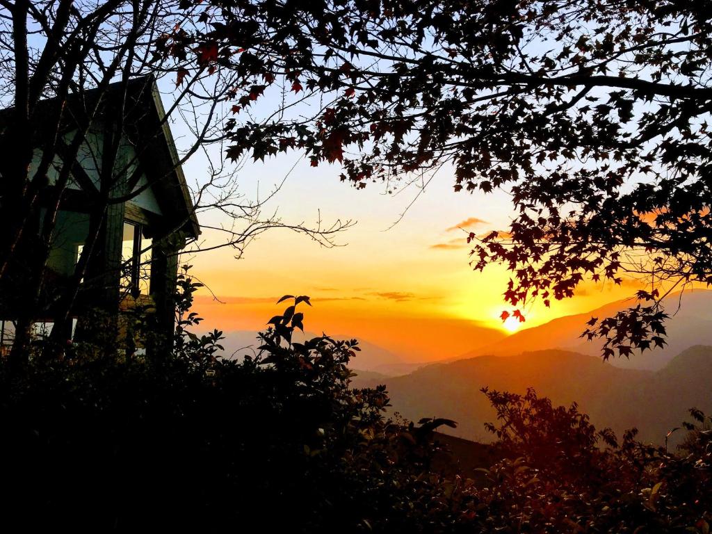 a sunset in the mountains with a house at Top Cloud Villa in Renai