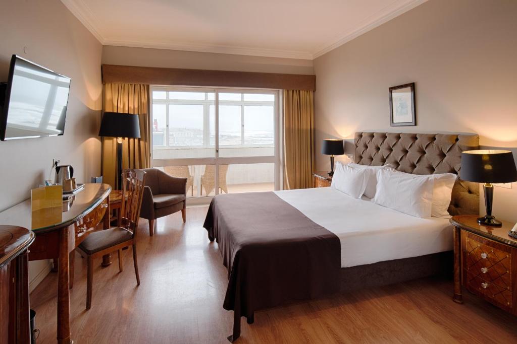 um quarto de hotel com uma cama grande e uma secretária em Golden Tulip Porto Gaia Hotel em Vila Nova de Gaia