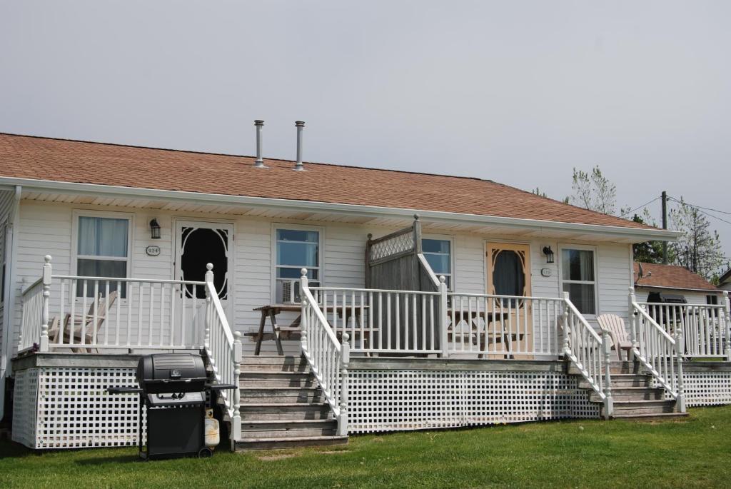 a house with a white porch and stairs at Shining Waters - Ingleside Cottages in Cavendish