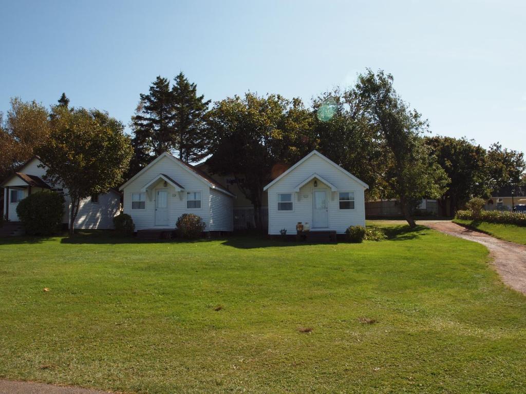 two white houses in a yard with a green lawn at Shining Waters - Ingleside Cottages in Cavendish