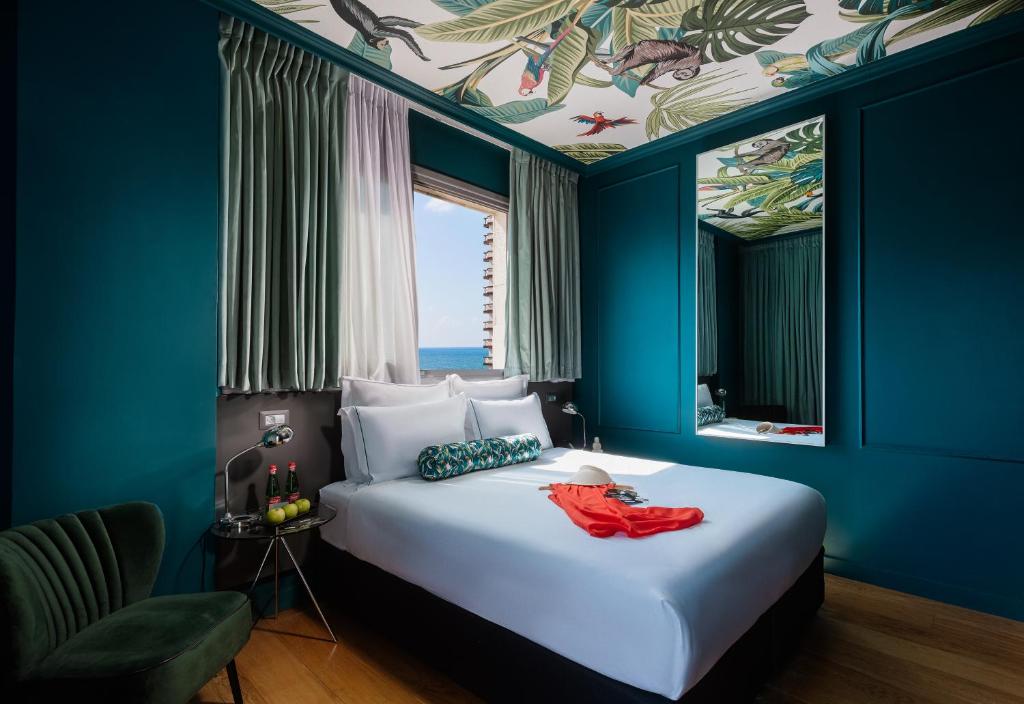 1 dormitorio con 1 cama grande, paredes azules y ventana en Brown Seaside a member of Brown Hotels, en Tel Aviv