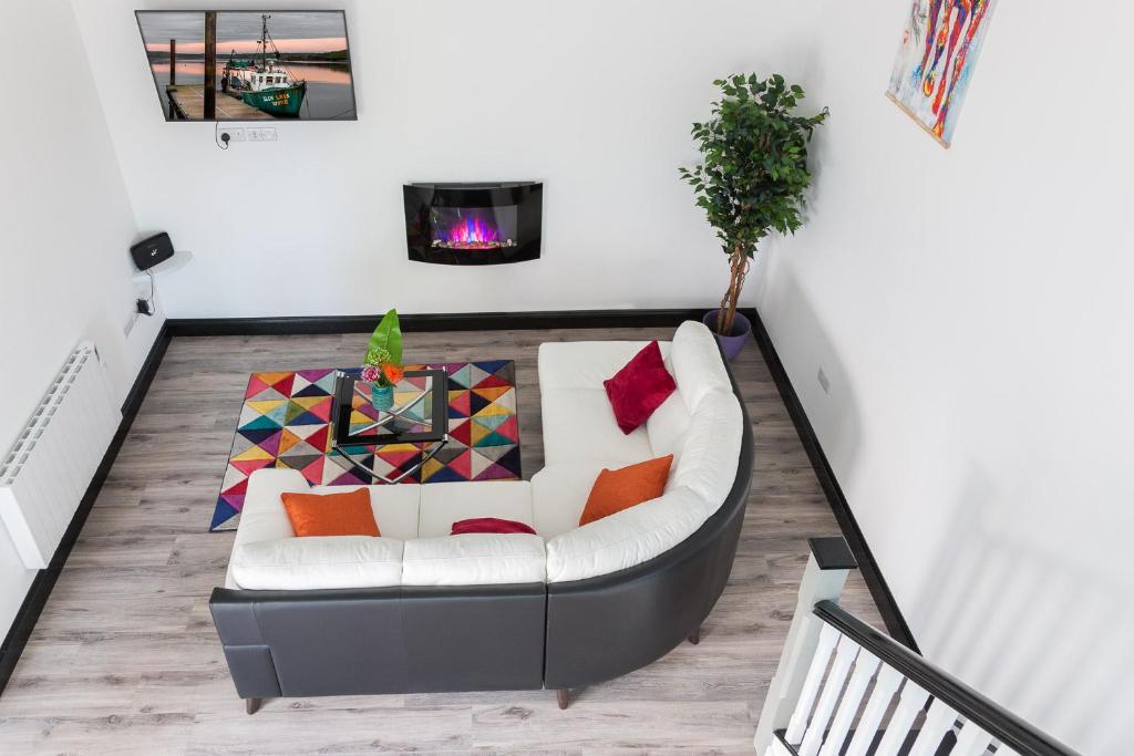 a living room with a white couch with colorful pillows at Curragh House Lodges in Kinsale