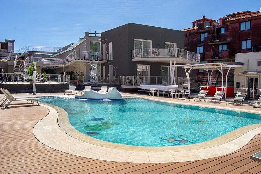 een groot zwembad met stoelen en een gebouw bij Ciclope Resort in Acitrezza
