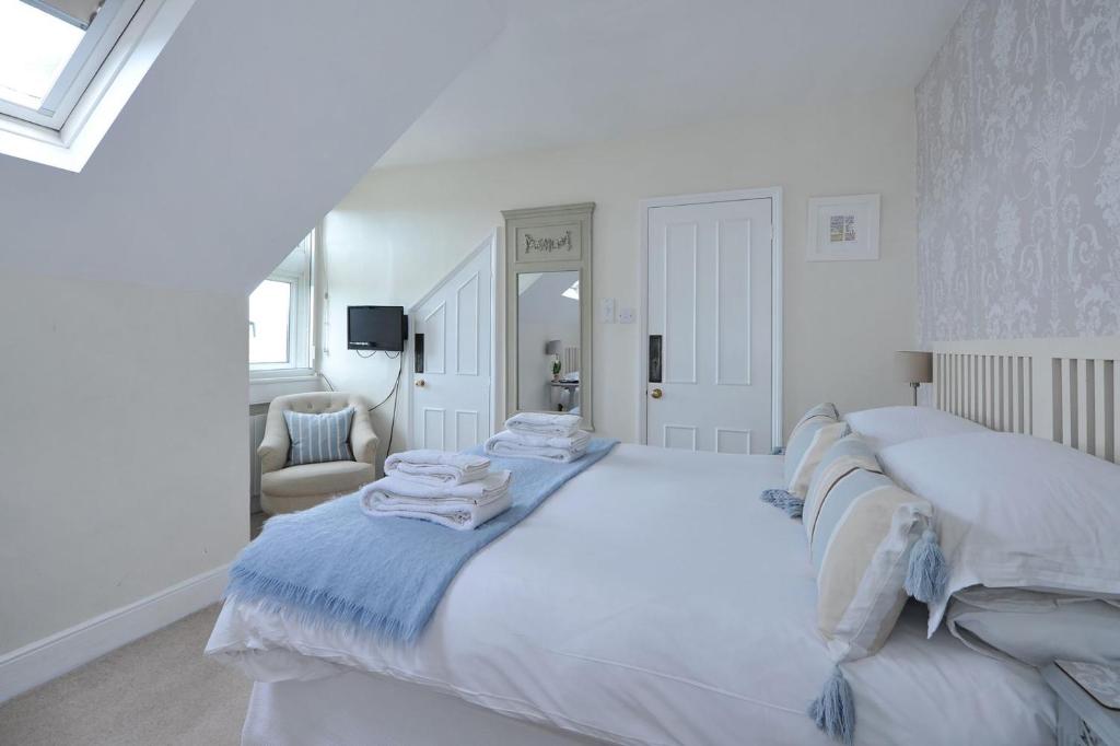 a white bedroom with a large bed with towels on it at Abbey Rise bed and breakfast in Bath