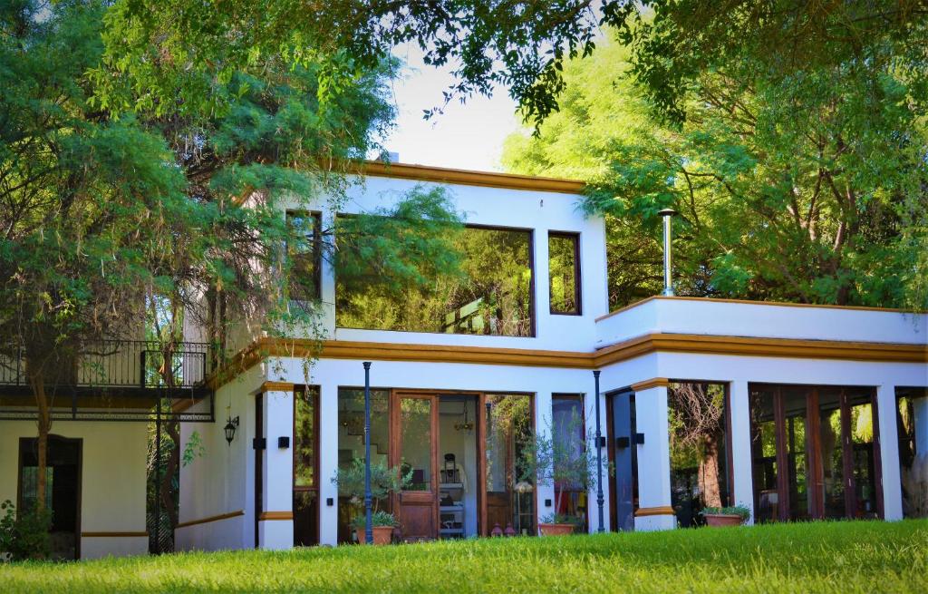 a white house with glass doors and trees at Estancia del Olivo in Chilecito