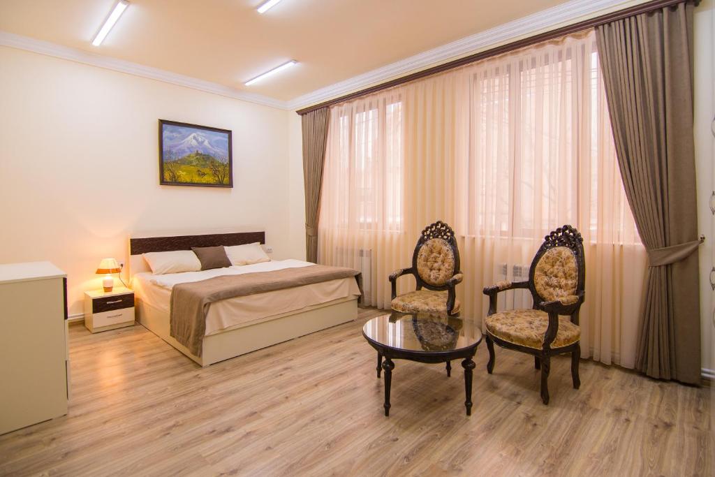 1 dormitorio con 1 cama, 2 sillas y mesa en Tatev Hotel and Tours en Ereván