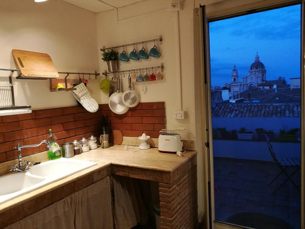 uma cozinha com um balcão com um lavatório e uma janela em L'attico di Rosetta em Catânia