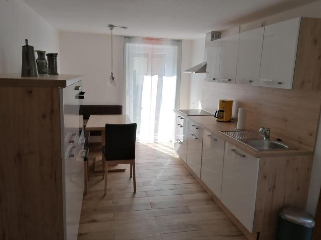 a kitchen with white cabinets and a table with a chair at FW Knöppel Sonja und Stefan in Zapfendorf