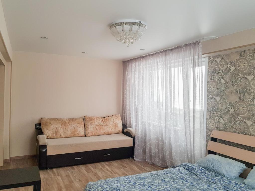a living room with a couch and a window at Апартаменты Кристалл на Пушкина 12 in Yurga