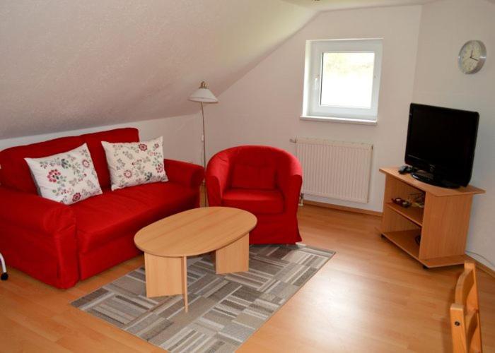 a living room with a red couch and a red chair at Ferienwohnung Harry im Riesengebirge in Dolní Lánov
