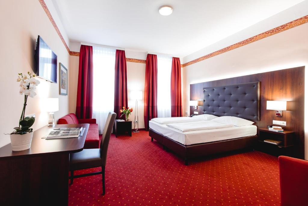 a hotel room with a large bed and a desk at Hotel Allegro Wien in Vienna
