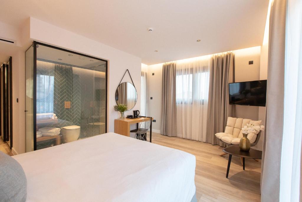 a bedroom with a large white bed and a living room at Old Port Hotel in Limassol