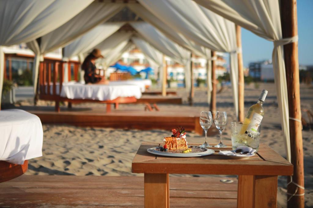 Una mesa con un trozo de pastel y copas de vino en la playa. en San Agustin Paracas, en Paracas