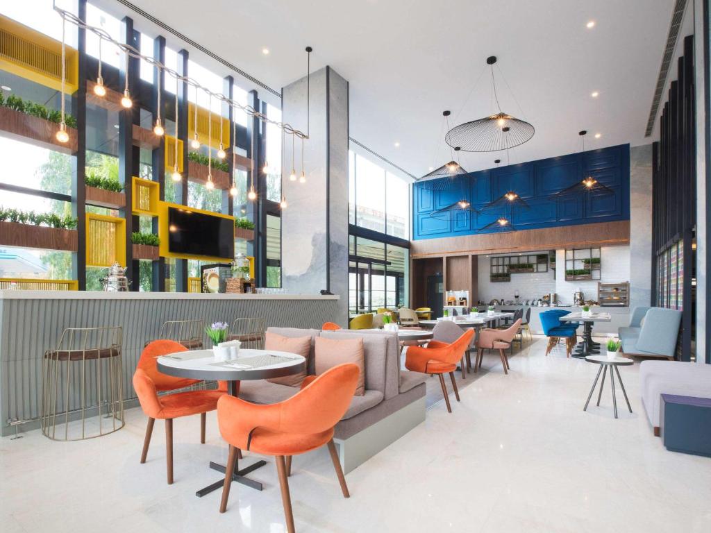 un vestíbulo de un restaurante con mesas y sillas naranjas en ibis Styles Izmir Bornova, en Izmir