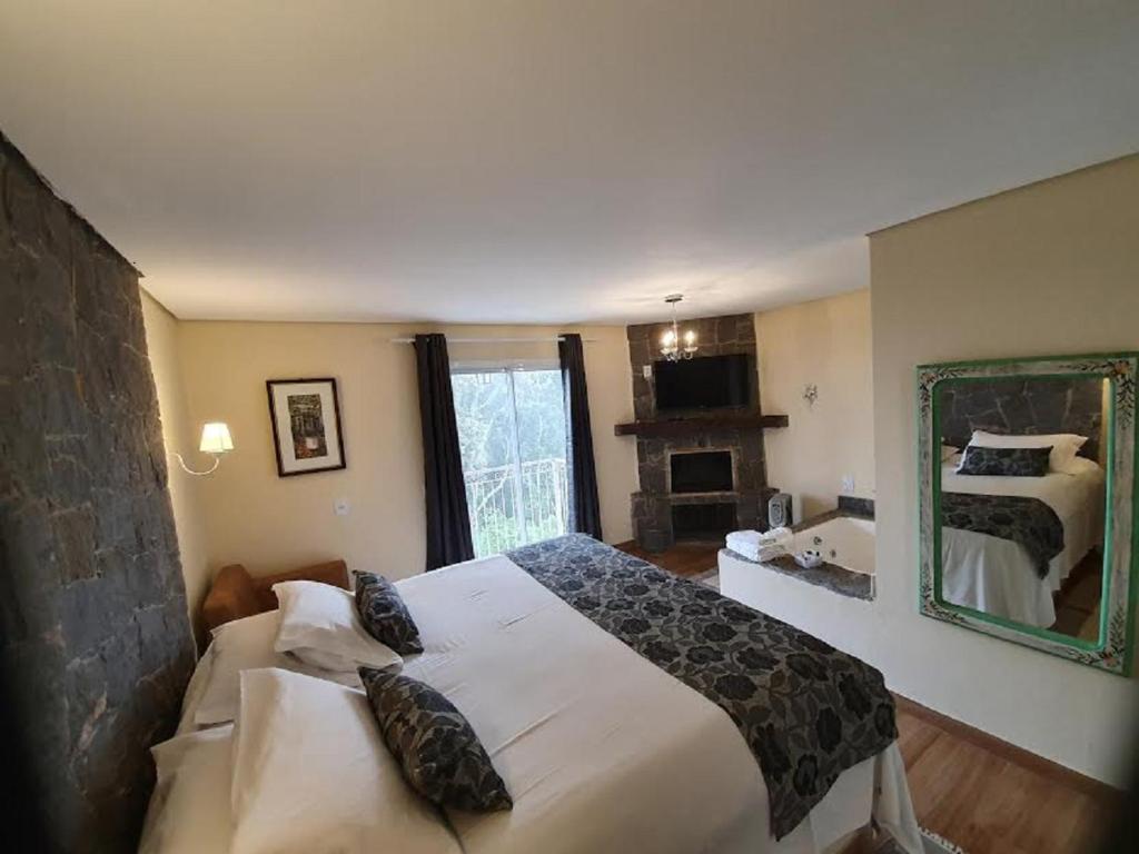 una camera con un grande letto e uno specchio di Pousada Villa Hegus a Campos do Jordão