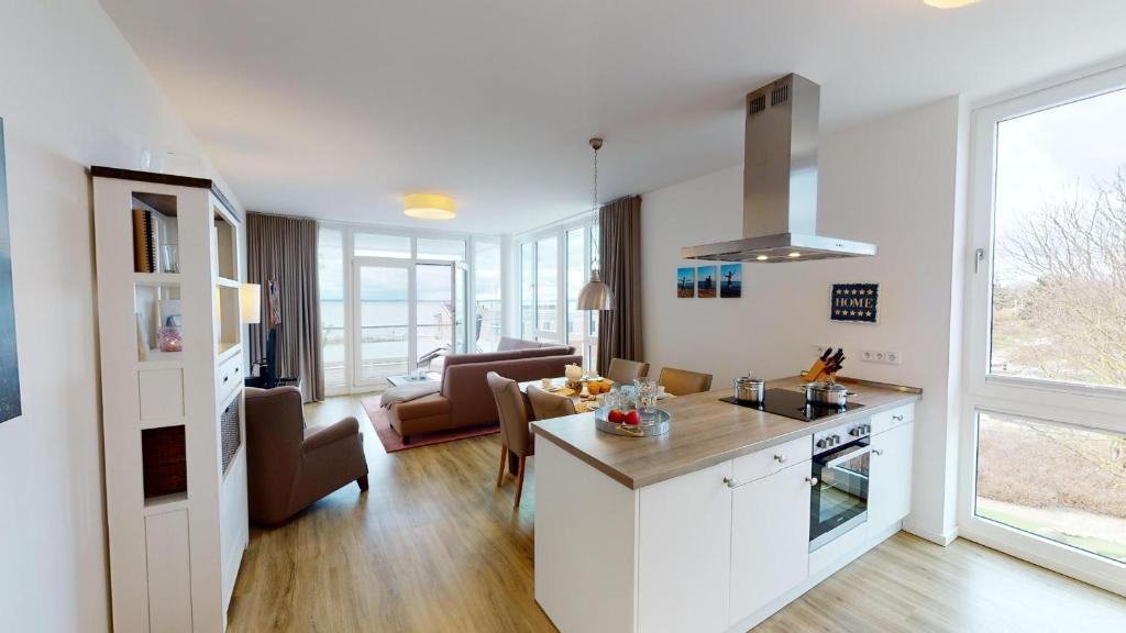 a kitchen and living room with white cabinets and a couch at Südkap E-04 in Pelzerhaken