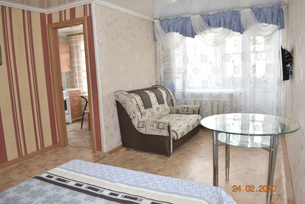 sala de estar con silla y mesa de cristal en 1 комнатные апартаменты на Абая 134, en Kokshetau