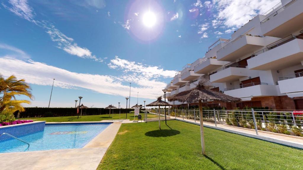 プレヤス・デ・オリフエラにあるCampoamor Golf 156 Terrazas Villamartin Family Resのスイミングプール付きのホテルの側面の景色を望めます。
