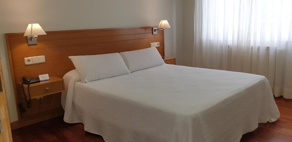 a bedroom with a white bed with two pillows at Hotel Arteixo in Arteixo