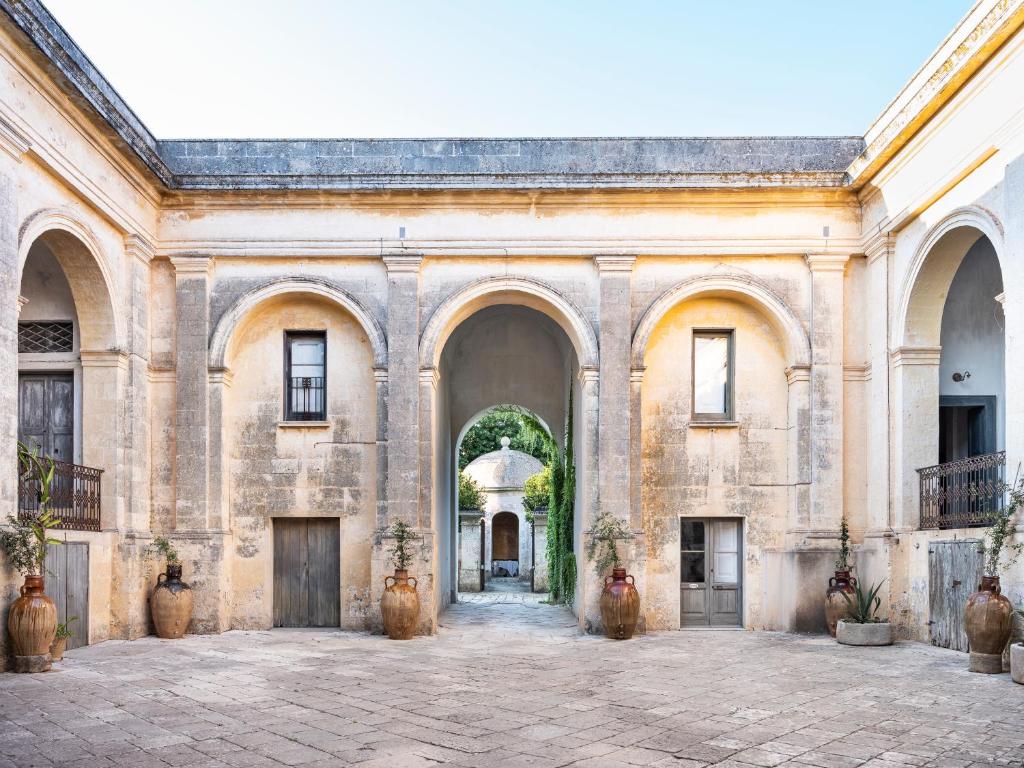 a large stone building with arches and a courtyard at Palazzo Daniele in Gagliano del Capo