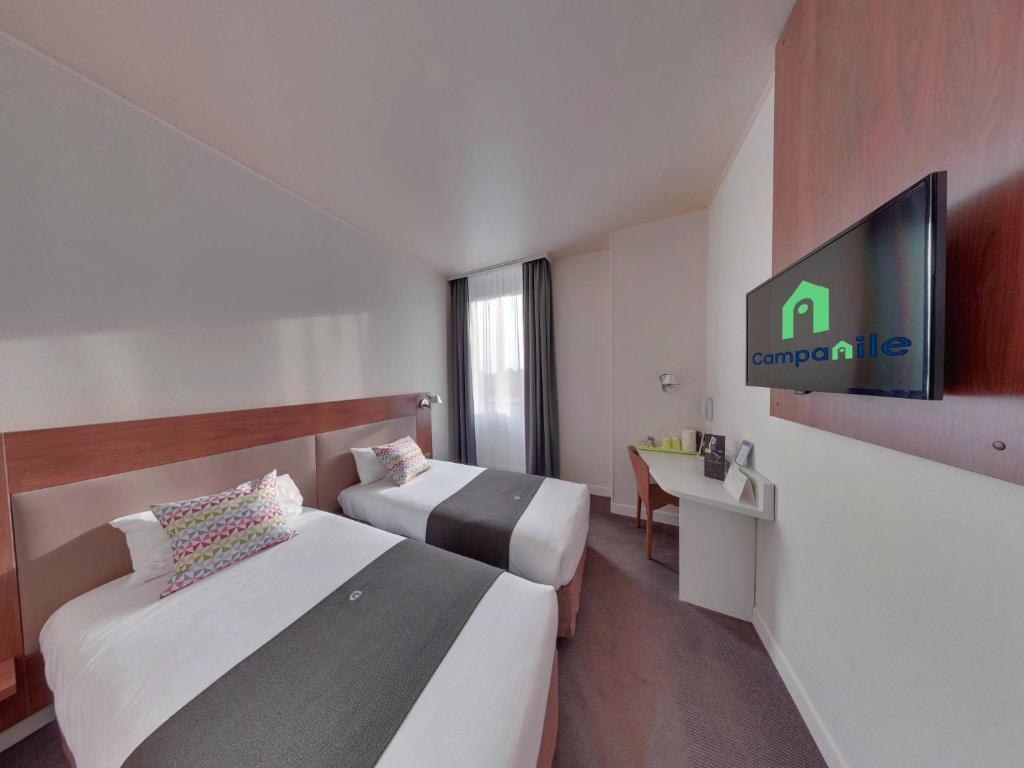 a hotel room with two beds and a flat screen tv at Campanile Orléans Centre Gare in Orléans
