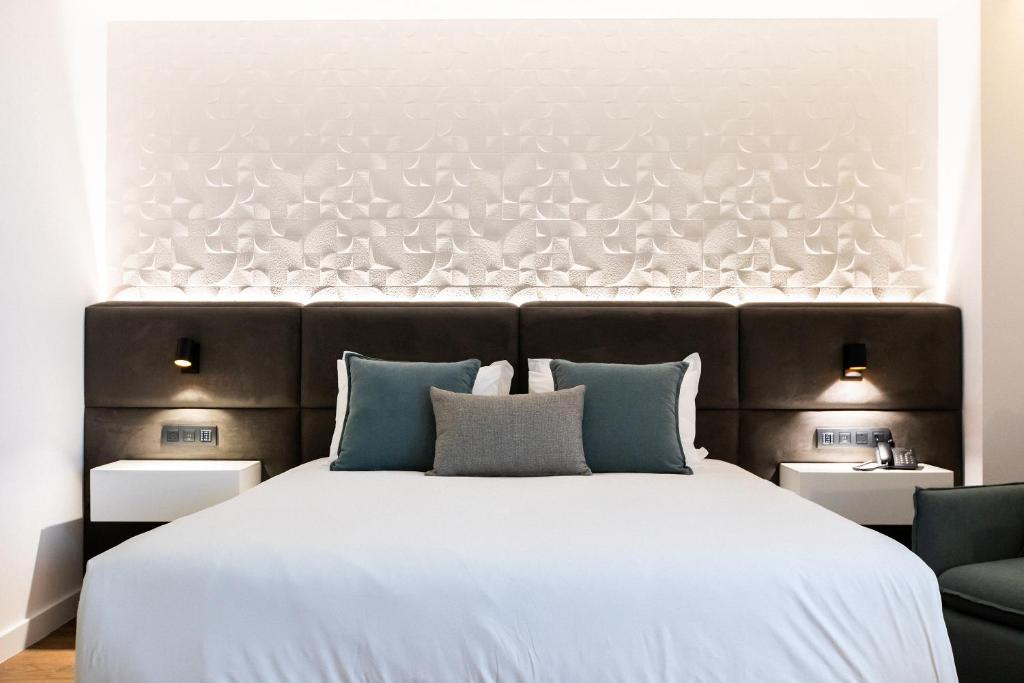 a bedroom with a large white bed with blue pillows at Old Port Hotel in Limassol