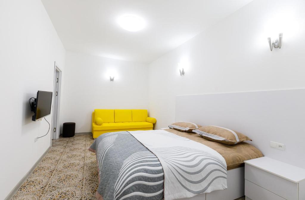 een slaapkamer met een bed en een gele stoel bij Уютная одна комнатная квартира на Башлыке in Tasjkent